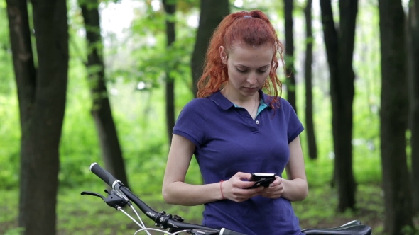 Girl Sitting on the Bike and Texting on Smartphone
