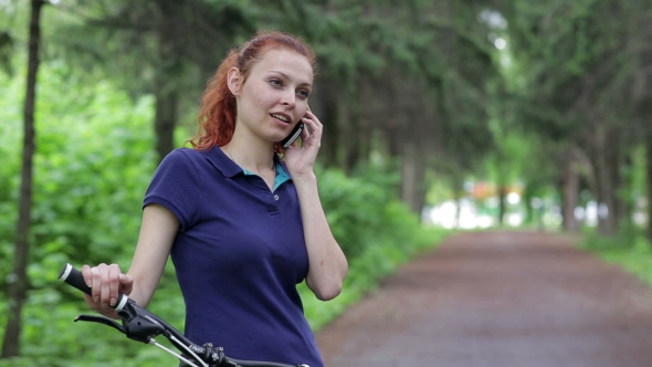 Young Woman on Bike in Park Talking on Cell Phone