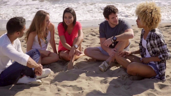 Group Of Diverse Young Friends Chatting On a Beach