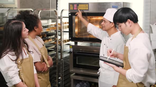 Male chef explains the electric oven to cooking class students for baking bread.