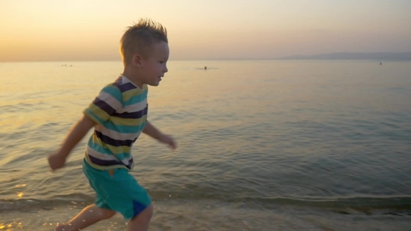 Smiling Boy Running Along The Sea