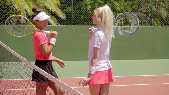 Pair Of Friends Talking On Tennis Court