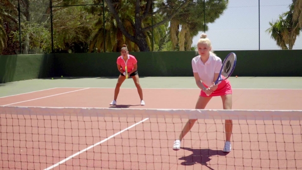 Two Pretty Women Playing a Game Of Tennis Doubles