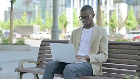 Rejecting African Man in Denial While Using Laptop Sitting Outdoor on Bench