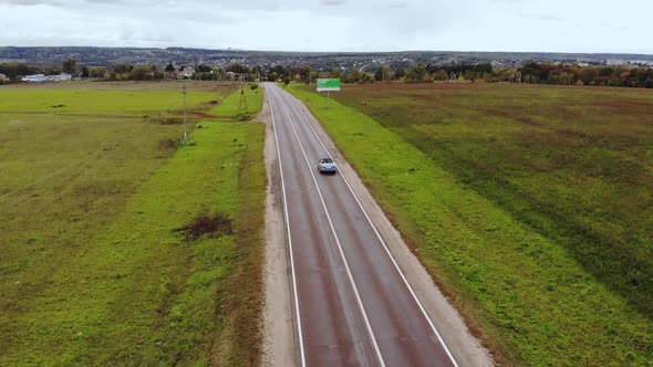 Car Drives Along Asphalt Road Running Among Country Fields