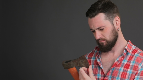 Bearded Man Checks The Sharpness Of The Ax