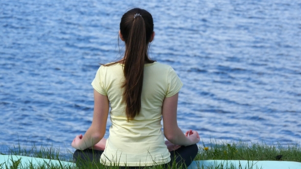 Young Woman Relaxing Meditating On The Beach.