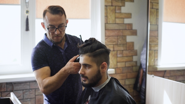 Handsome Bearded Barber Giving a Haircut To His Client 