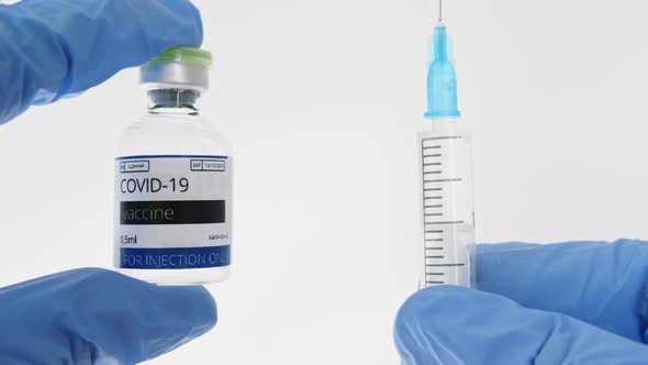 COVID19 Vaccine in Researcher Hands Doctor's Hand Holds a Syringe and a Vaccine Ampoule at the