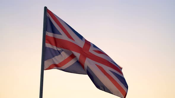 UK flag waving over sunset sky.