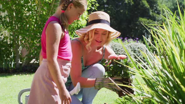 Caucasian mother and daughter taking care of plants outdoors
