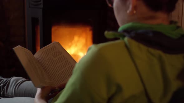 Young Woman Reading a Book Near Fireplace at Home