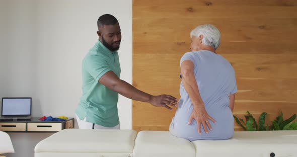 Video of african american male physiotherapist examining caucasian senior woman