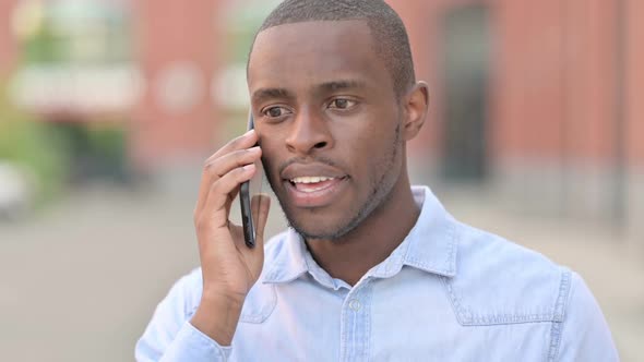 Outdoor Portrait of Cheerful African Man Talking on Smartphone