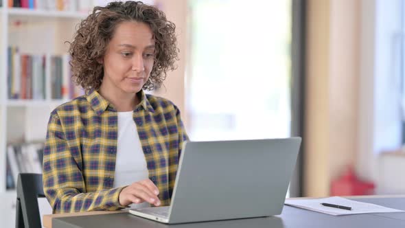 Young Mixed Race Woman Reacting To Loss on Laptop at Work 