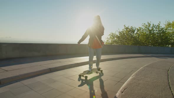 Cool Lovely Woman Skateboarding and Chatting on Cellphone at Sunrise