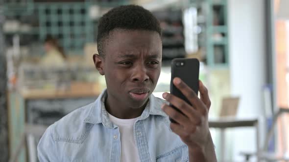 Portrait of Young African Man Reacting to Failure on Smartphone