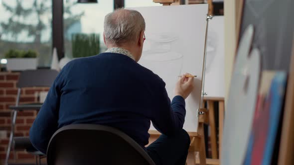 Senior Man Using Pencil to Sketch Inspiration Model in Creative Workshop