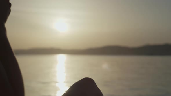 Closeup of a Glass of Cocktail at Sunset By the Ocean in the Hands