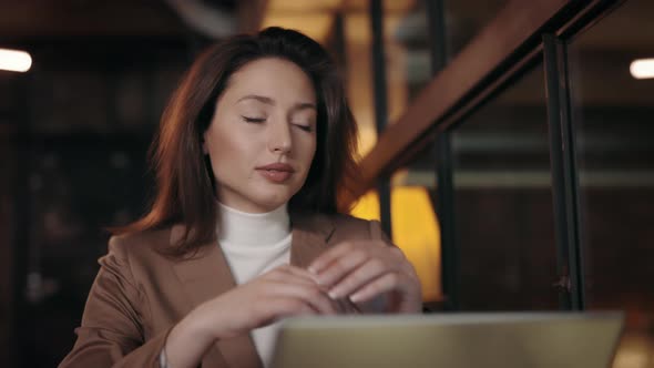 Dreamy Woman Looking Aside While Sitting at Cafe with Laptop