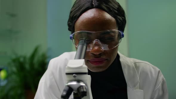 Closeup of African Researcher Woman Looking at Leaf Slide Under Microscope