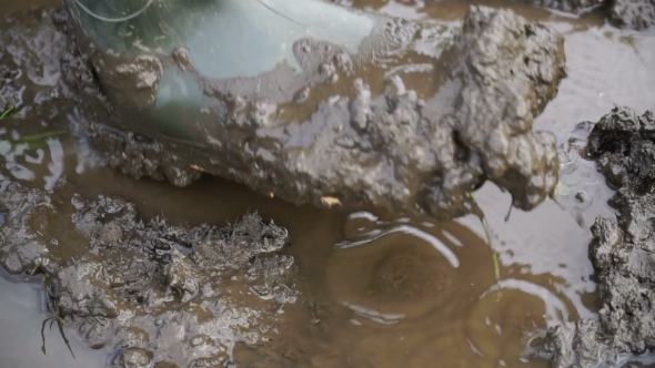 Man in Rubber Boots Walking on the Mud