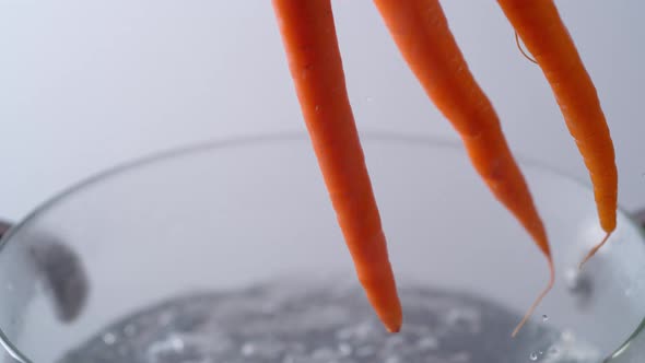 Camera follows cooking carrots in boiling water. Slow Motion.
