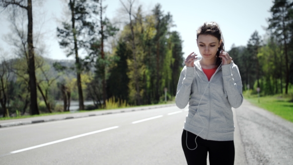 Beautiful Young Woman Runner Athlete Insert Her Earphones During Training 