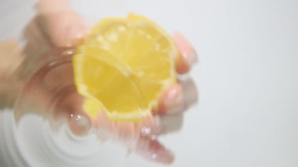 Droplets Of Water Fall From Lemon Half On Surface