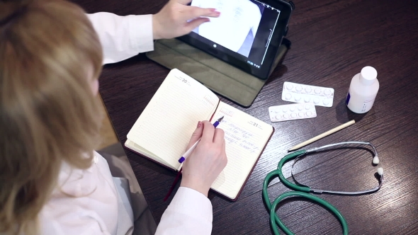 Doctor Working With Tablet Computer And Documents
