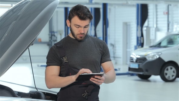 Mechanic Uses a Tablet At The Car Service