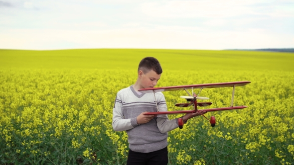 Handsome Child Holds Homemade Airplane On The Canola Background. 