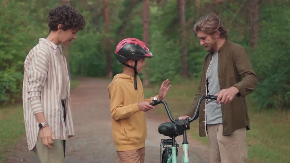 Boy Riding Bike In Forest With Parents