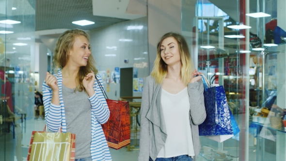 Two Attractive Women Go Through The Mall With Shopping Bags, Talking