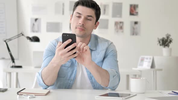 Casual Young Man Celebrating Success on Smartphone