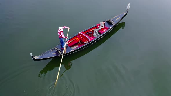 Gondolier putting gondola through river. Aerial view of gondolier carries tourists on gondola