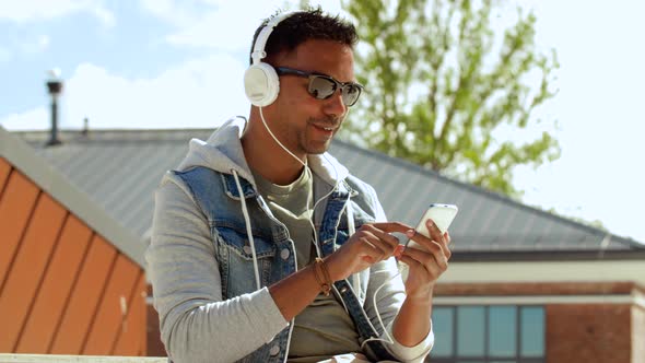 Man with Smartphone and Headphones on Roof Top