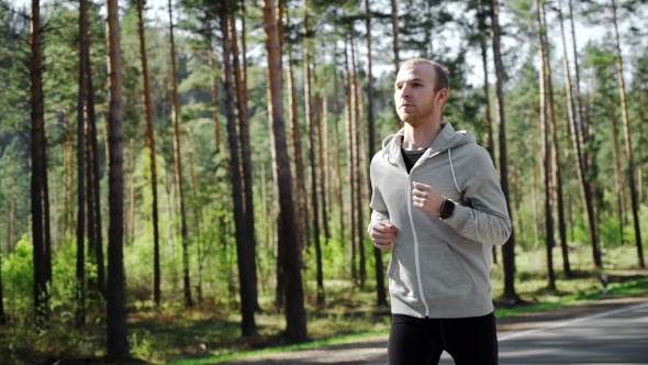 Man Running Looking At His Pulse Outside In Nature On Road With Smartwatch.