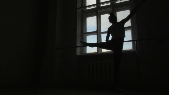 Silhouette Of a Ballet Dancer Exercising At The Barre By The Window