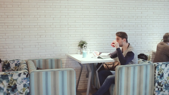 Young Man With Smartphone Sitting In Cafe