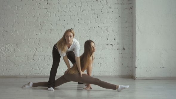 Yoga Trainer Helps Female Student To Stretch Legs And Do The Splits