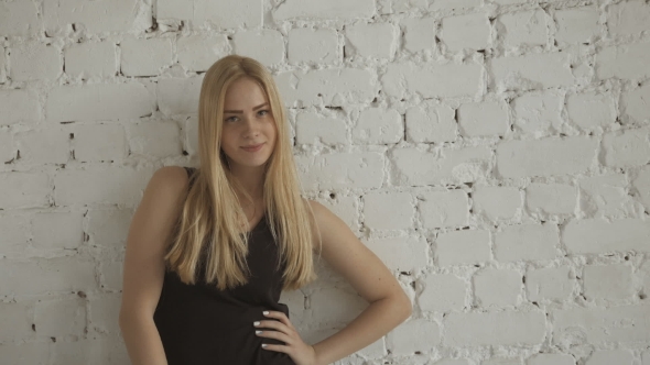 Smiling Cute Female Blonde Model Looking At Camera On  Brick Wall Background