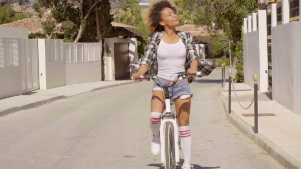 Young Woman Riding The Bicycle On The Road