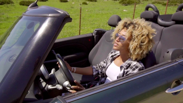 Trendy Young Woman Driving a Sports Car