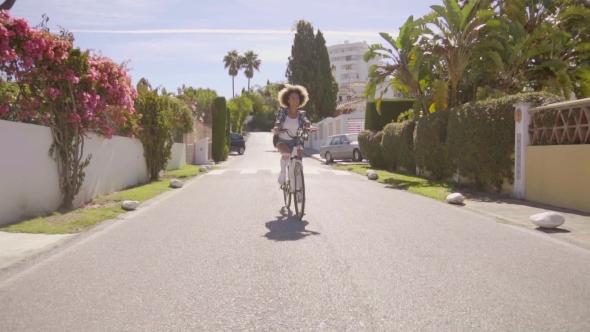 Young Woman Riding The Bicycle On The Road