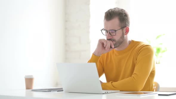 Man Thinking While Working on Laptop in Office