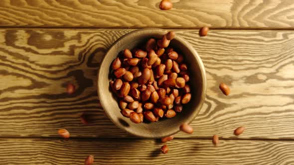 Peeled peanuts fall into a wooden dish on a table