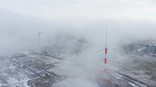 Wind turbine in a snowy landscape with early winter morning mist.