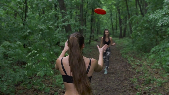 Two Slender Brunette In The Woods, Throwing a Frisbee Plate.