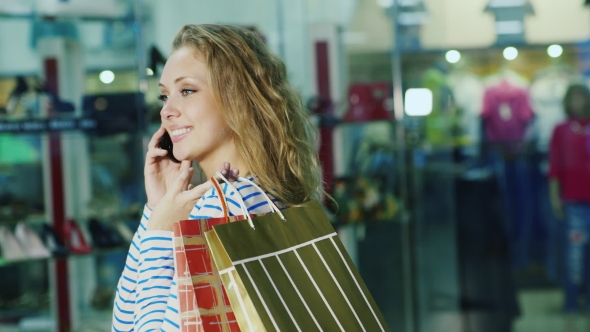 An Attractive Woman With Shopping Bags Talking On The Phone